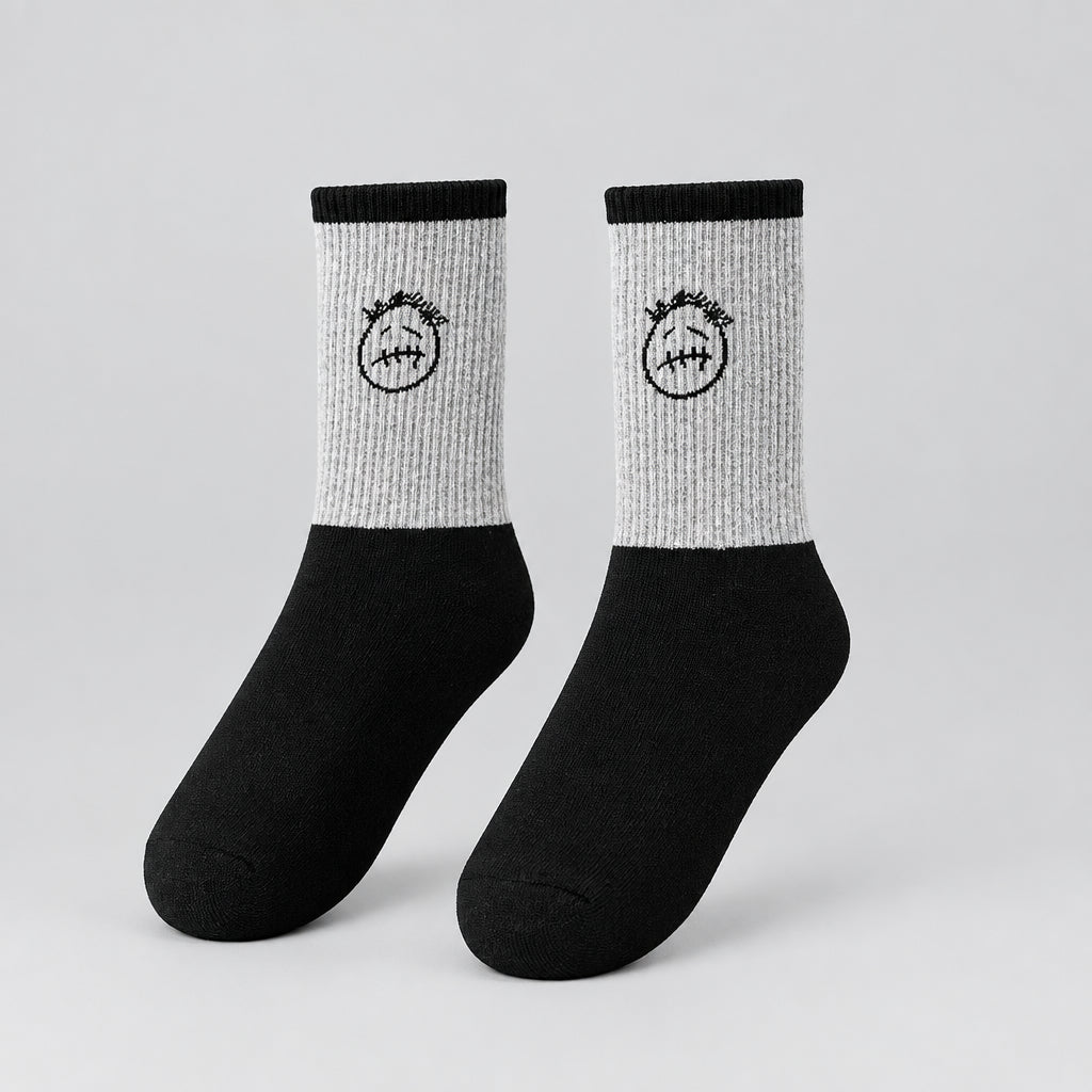 Gray and black crew socks with black stitched-face graphics and black cuffs, angled view