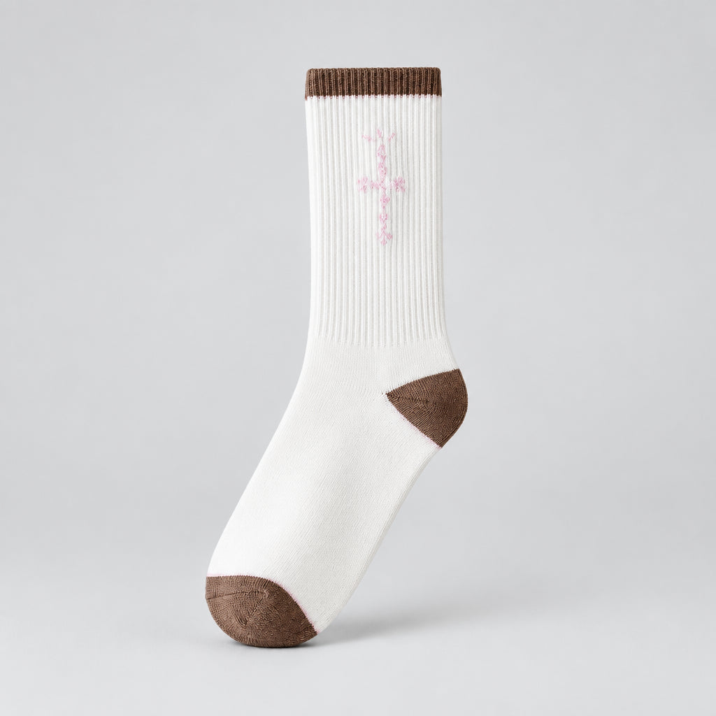 White crew sock with pale pink cross-shaped lettering and brown cuff, heel, and toe, angled view