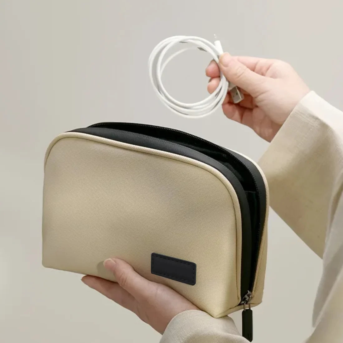 Hands holding the beige organizer while placing a coiled cable inside.