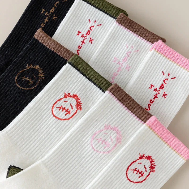 Close-up of black and white ribbed socks with face and lettering graphics and brown, olive and pink cuffs.