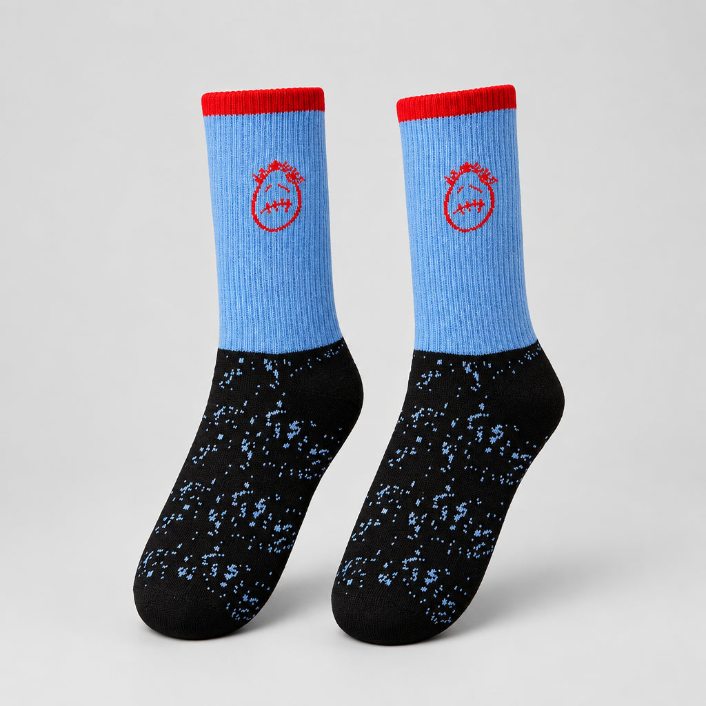 Blue and black crew socks with red cuffs, red stitched-face graphics, and speckled feet, angled view