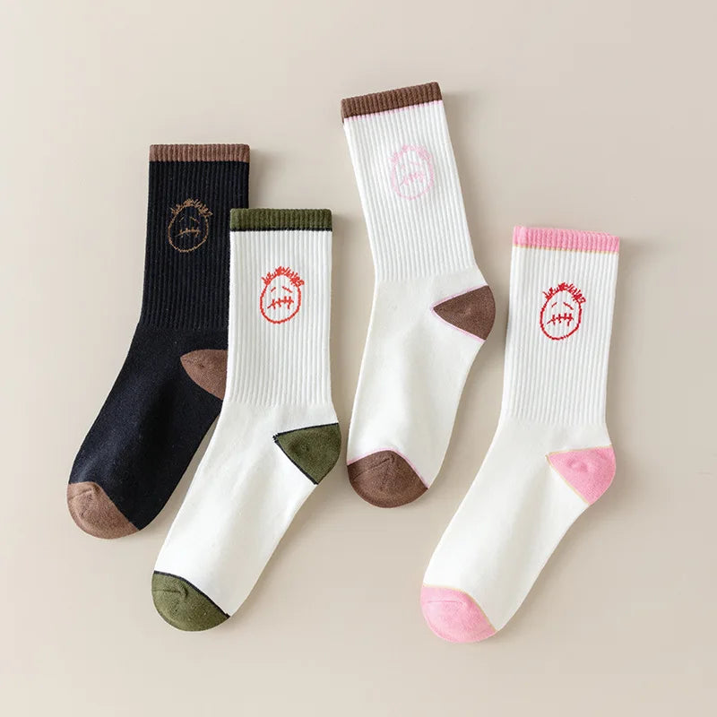 Black and white socks laid flat with face graphics and brown, olive and pink cuffs, heels and toes.