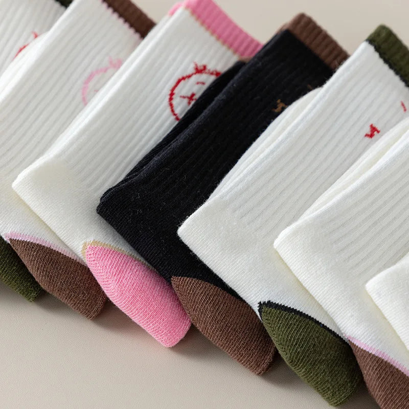 Close-up of overlapping black and white socks with brown, pink and olive heels and cuffs.