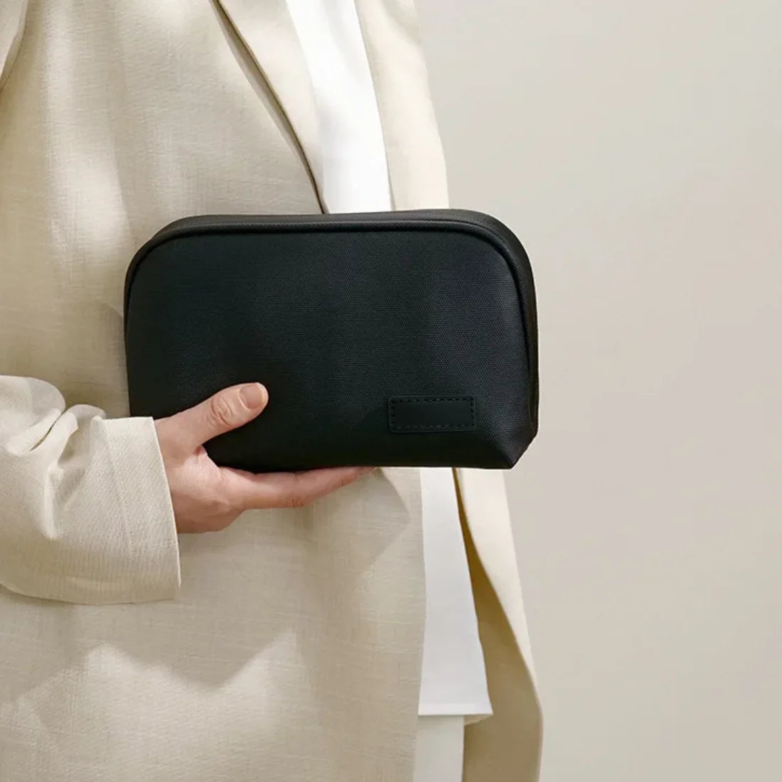 Black organizer pouch held against a light-colored coat.