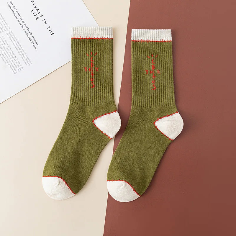 Olive green crew socks with red cross-shaped lettering and white cuffs, heels, and toes, flat lay