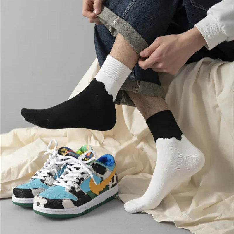 Person wearing black and white socks with colorful sneakers on a neutral background