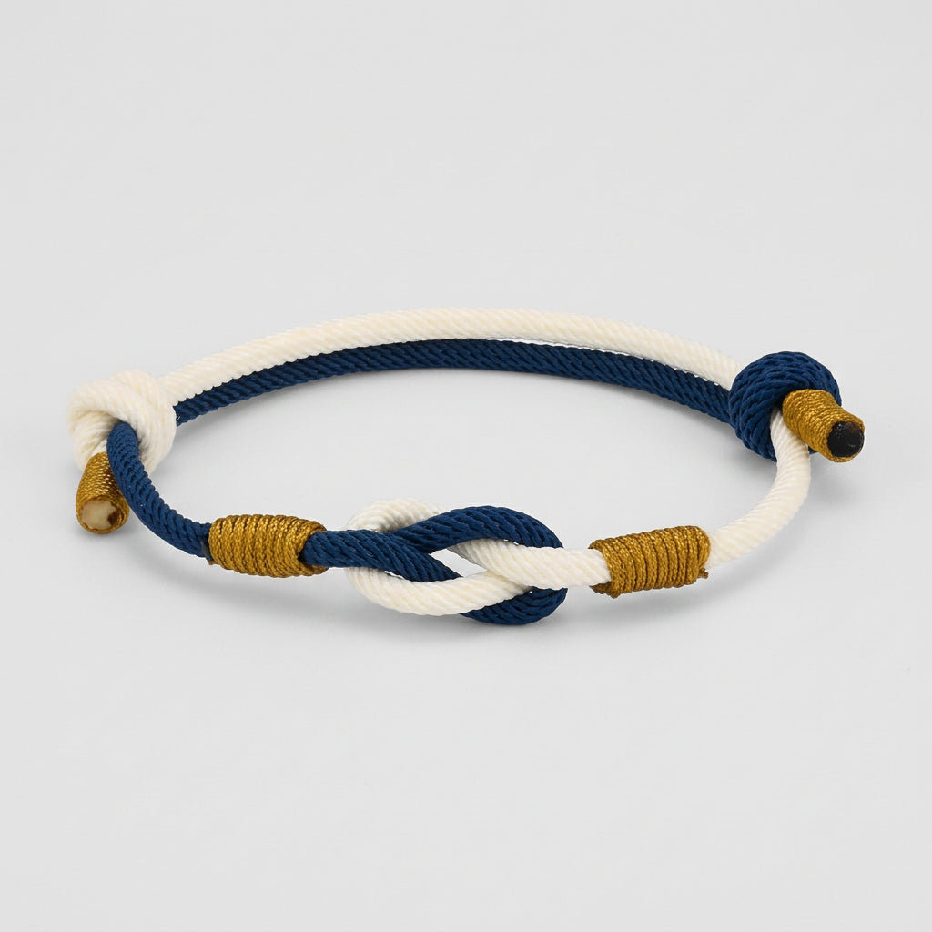 Nautical-style bracelet with blue, white, and gold ropes on a white background
