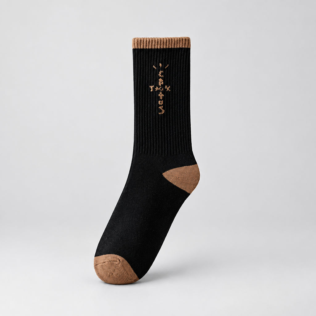 Black crew sock with tan cross-shaped lettering and tan cuff, heel, and toe, angled view
