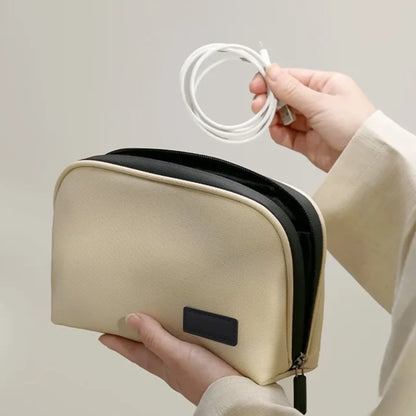Hands holding the beige organizer while placing a coiled cable inside.