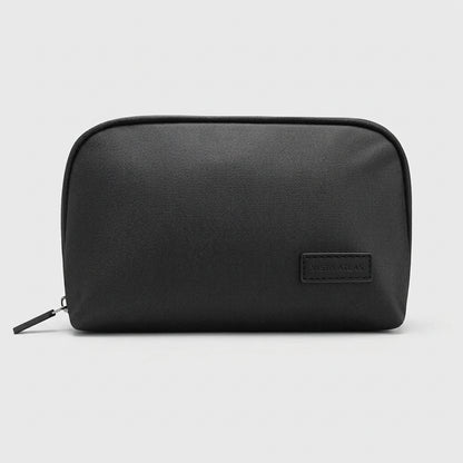 Black organizer pouch shown closed with its zipper pull and stitched label patch.