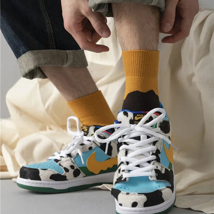 Colorful sneakers with a cow print worn by a person, paired with yellow socks.