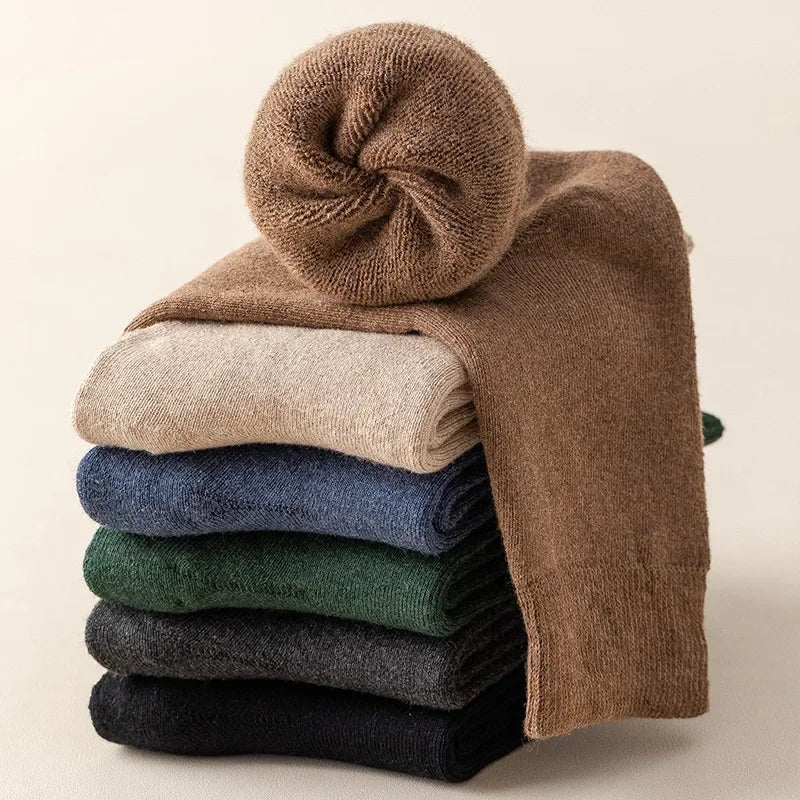 Stack of folded brown, beige, blue, green, and black socks on a beige background