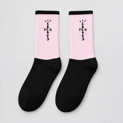 Pink and black crew socks with black cuffs and cross-shaped lettering, angled view