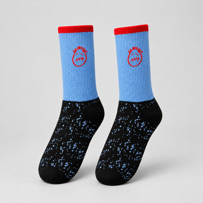 Blue and black crew socks with red cuffs, red stitched-face graphics, and speckled feet, angled view