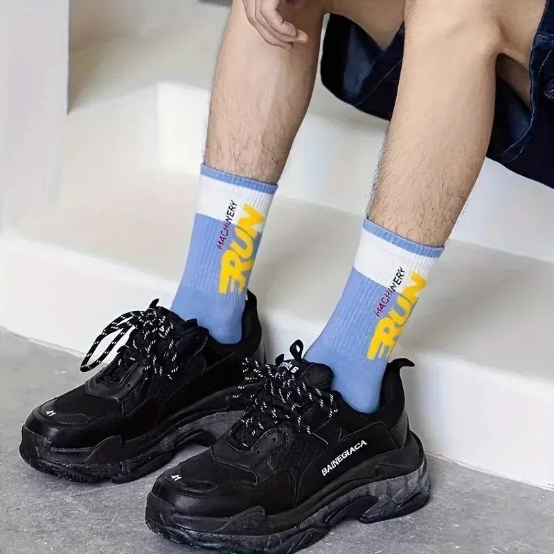 Person wearing black sneakers and blue socks with yellow text on a neutral background