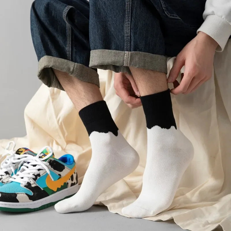 Person wearing black and white socks with colorful sneakers on a neutral background