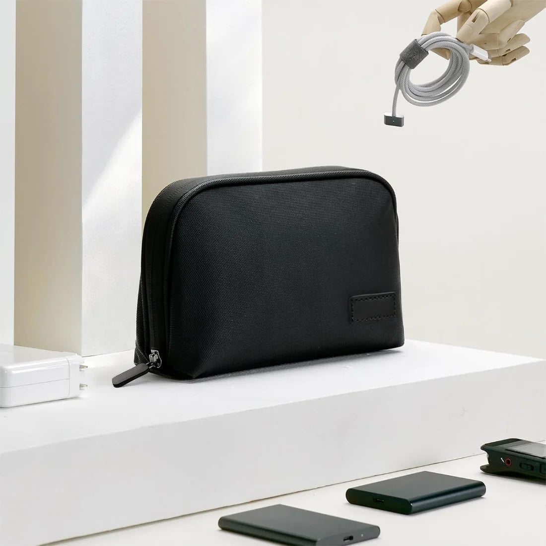 Black organizer pouch on a desk beside example phones, charger and cable.