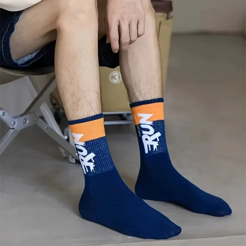 Person wearing blue socks with orange and white accents, sitting on a chair.