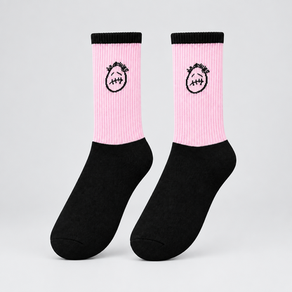 Pink and black crew socks with black stitched-face graphics and black cuffs, angled view