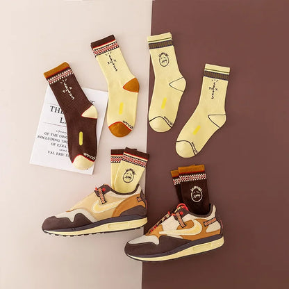 Brown and pale yellow graphic socks arranged beside matching sneakers.