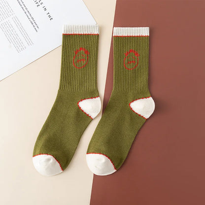 Olive green crew socks with red stitched-face graphics and white cuffs, heels, and toes, flat lay
