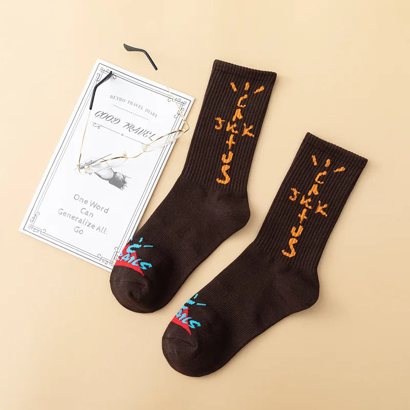 Dark brown crew socks with orange cross-shaped lettering and colorful toe graphics, flat lay