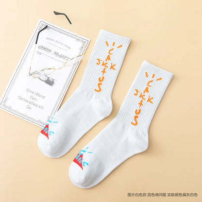 White crew socks with orange cross-shaped lettering and colorful toe graphics, flat lay