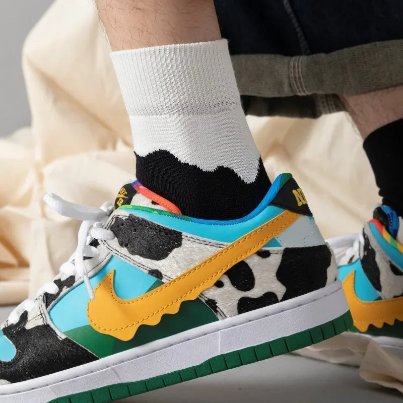 Colorful sneakers with a cow print and yellow Nike logo worn by a person.