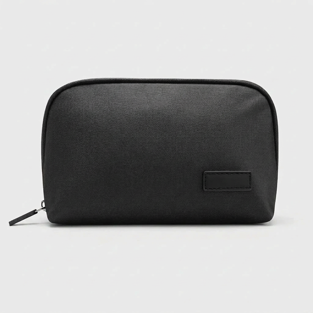 Black tech organizer pouch shown closed with zipper pull and plain stitched patch on a white studio background.